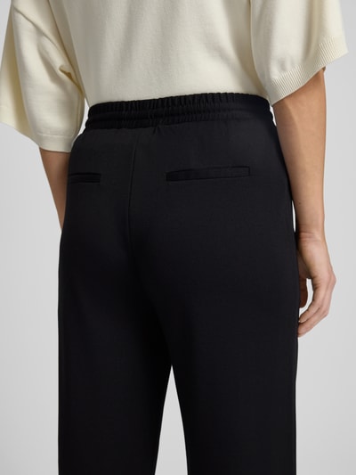 Frauenmodel trägt Stoffhose mit elastischem Bund Modell 'NANNI' von FREE/QUENT, schwarzer Stoff, Form locker, Nahaufnahme Rückansicht.