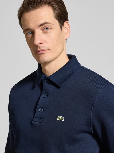 Männermodel trägt Regular Fit Sweatshirt aus reiner Baumwolle von Lacoste in Dunkelblau, Optik: Unifarben, Logo-Stitching, Nahaufnahme Oberkörper.