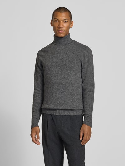 Männermodel trägt Slim Fit Rollkragenpullover aus Woll-Mix Modell 'Karl' von Casual Friday in Grau mit gerippten Abschlüssen, Ganzkörperansicht von vorne.