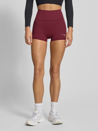 Frauenmodel trägt PUMA x HYROX - Leggings mit elastischem Bund in Bordeaux, Skinny-Fit, Label-Print, Elastischer-Material-Mix, Nahaufnahme Oberkörper von vorne.
