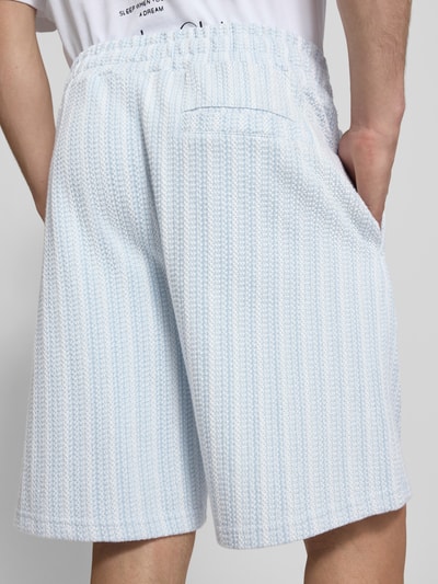 Mężczyznamodel nosi szorty Straight Fit Shorts mit Strukturmuster Modell 'Forno' od Pegador z bawełny, błękitno-białe pasy, elastyczny pas, szerokość w rozmiarze M 42 cm, długość wewnętrzna nogawki 23 cm, fakturowany wzór; widok tyłu, zdjęcie całej sylwetki.