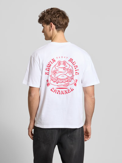 Männermodel trägt weißes T-Shirt aus reiner Baumwolle Modell 'MUSIC CHANNEL' von Edwin mit rotem Print und geradem Schnitt, Ganzkörperansicht Rückansicht.