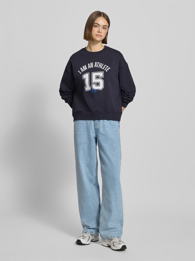 Frauenmodel trägt Relaxed Fit Sweatshirt aus reiner Baumwolle von Marc O'Polo Denim in Optik: Unifarben mit Motiv-Print, Langarm, Rundhals, Sweat-Material, Label-Stitching-Applikation, ganzkörperansicht von vorne.