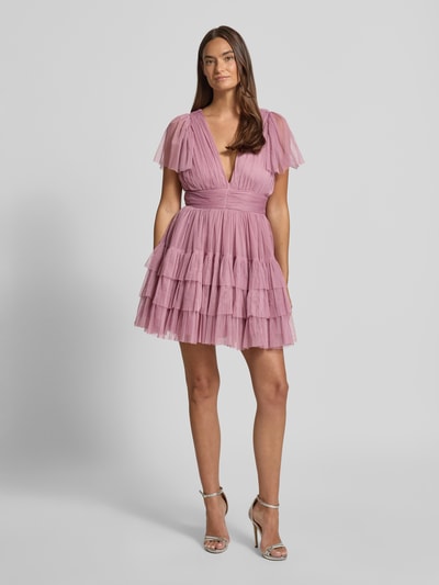 Modelka nosi 'Cocktailkleid mit tiefem V-Ausschnitt' od LACE & BEADS, różowy tiul, fason A-linia, pasek w talii, widok całej sylwetki z przodu.