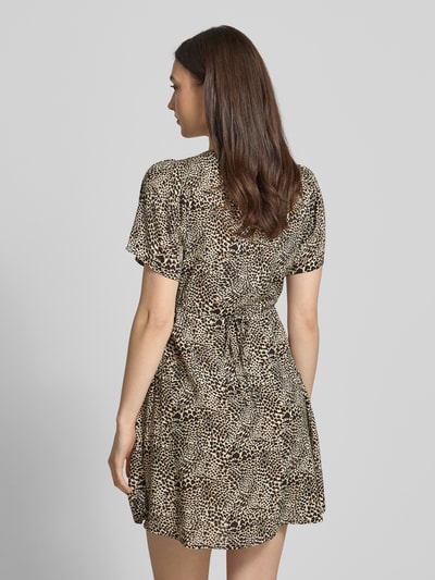 Frauenmodel trägt Minikleid aus reiner Viskose Modell 'EVIDA' von Only mit Allover-Muster, tailliert, kurze Ärmel, Rückansicht.