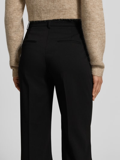 Frauenmodel trägt Flared Fit Hose mit Viskose-Anteil von MYON, schwarze Bügelfaltenhose, weiche Textur, Ganzkörperansicht Rückansicht.