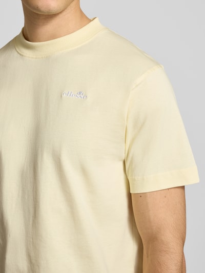 Męski model nosi T-Shirt mit Label-Stitching Modell 'ACCIANO CLASSIC' od Ellesse, bawełna, krój regular fit, kremowy, zbliżenie na górną część torsu.