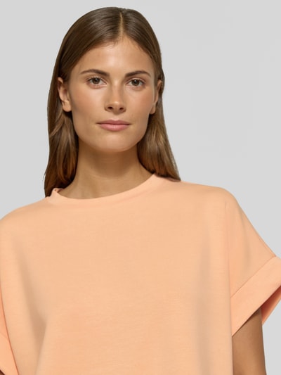 Frauenmodel trägt T-Shirt mit elastischen Abschlüssen von Rich & Royal in Pfirsich, Modal-Mix, Relaxed Fit, Rundhalsausschnitt, Nahaufnahme Oberkörper.