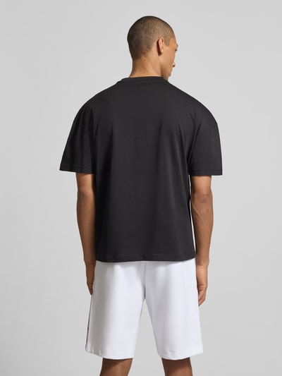 Męski model nosi T-shirt mit Logo und Rundhalsausschnitt von EA7 Emporio Armani, czarna bawełna, krój regular fit, długość tyłu w rozmiarze M: 68 cm, całkowity widok z tyłu.