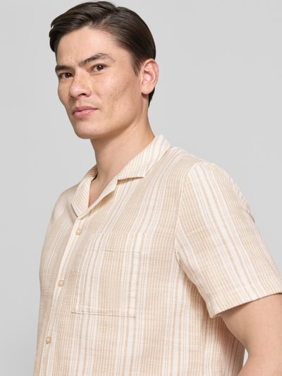 Männermodel trägt Regular Fit Freizeithemd aus reiner Baumwolle von s.Oliver RED LABEL, gestreiftes Allover-Muster, beige-weiß, Nahaufnahme Oberkörper.