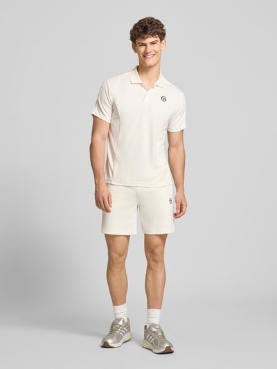 Männermodel trägt Shorts mit Logo-Stitching Modell 'EGEO' von SERGIO TACCHINI in Creme, lockerer Schnitt, seitliche Taschen, Ganzkörperansicht von vorne. Herren Shorts, Baumwoll-Mix mit Stretch, elastischer Bund, Kordelzug.