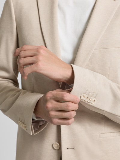Männermodel trägt 2-Knopf-Sakko mit Reverskragen von MCNEAL in Beige, Material-Mix mit Viskose-Anteil, Nahaufnahme Oberkörper.