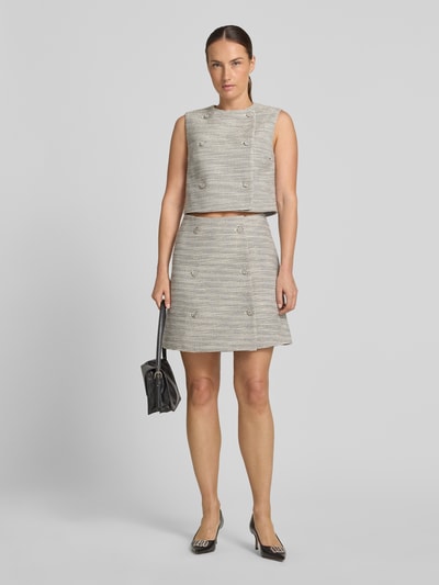 Frauenmodel trägt eng anliegenden Mini-Rock mit doppelreihiger Knopfleiste Modell 'RALINEA' von HUGO in Grau-Beige-Tönen, Ganzkörperansicht von vorne, Damen Mini-Rock von HUGO.