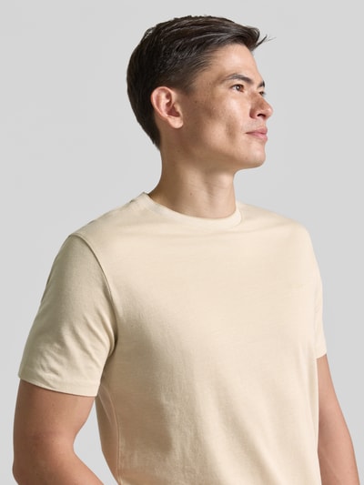Männermodel trägt T-Shirt mit Rundhalsausschnitt und Label-Stitching von Gant in Beige, reine Baumwolle, Regular Fit, Nahaufnahme Oberkörper.