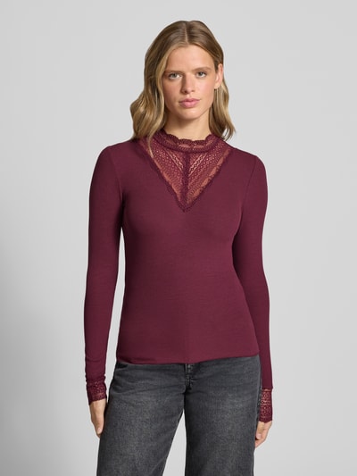 Frauenmodel trägt Slim Fit Langarmshirt aus Viskose-Mix Modell 'TILDE' von ONLY in Dunkelrot, Spitzen-Details, Damen Langarmshirt, Ganzkörperansicht von vorne.