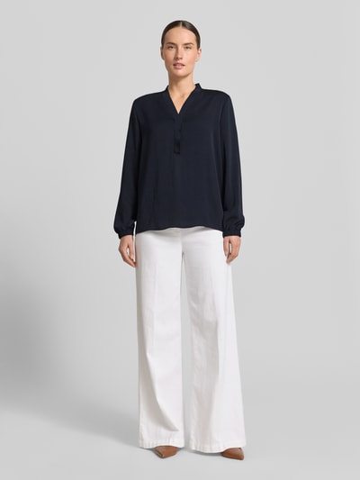 Frauenmodel trägt Bluse mit V-Ausschnitt und Label-Detail von Marc Cain in Dunkelblau, Loose-Fit, elastische Ärmelabschlüsse, Ganzkörperansicht von vorne, Rückenlänge bei Größe 36: 46 cm, Ärmellänge bei Größe 36: 60 cm.