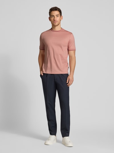 Męski model nosi Slim Fit T-Shirt aus reiner Baumwolle Modell 'H-TESSLER 238' von BOSS, różowy kolor, kontrastowe szwy, okrągły dekolt, krótki rękaw, krój slim fit, bawełna, jednolity wzór, całopostaciowy widok z przodu.