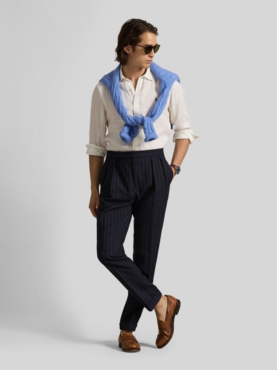Mannenmodel draagt Slim Fit Freizeithemd aus reinem Leinen van Polo Ralph Lauren in effen wit, puur linnen, button-down kraag, lange mouw, logo-stitching, afgeronde zoom, sportmanchet, flammengaren, volledige knoopsluiting, gecombineerd met donkerblauwe broek en lichtblauwe trui, vooraanzicht hele lichaam.