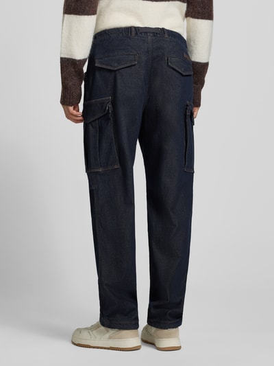 Männermodel trägt Straight Fit Jeans mit Cargotaschen von Armani Exchange in dunklem Denim mit mehreren Taschen, Ganzkörperansicht Rückansicht.