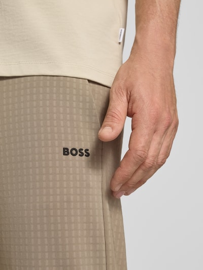 Männermodel trägt Tapered Fit Hose mit Waffelstrukturmuster Modell 'TERRACE' von BOSS Green in Beige mit Optik:Allover-Muster, Nahaufnahme Oberschenkel.