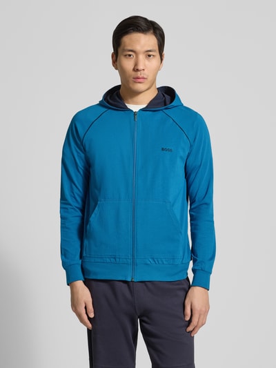 Männermodel trägt Regular Fit Sweatjacke aus Baumwoll-Mix von BOSS, Optik: Unifarben, Passform: Regular-Fit, Verschluss: Reißverschluss, Label-Stitching-Applikation, Kontraststreifen, Kragenform: Kapuze, Ärmelform: Langarm, Ärmelabschluss: Gerippt, Rumpfabschluss: Gerippt, Taschen: Kängurutasche, Materialverarbeitung: Sweat, Material: Baumwoll-Mix, Ganzkörperansicht von vorne.