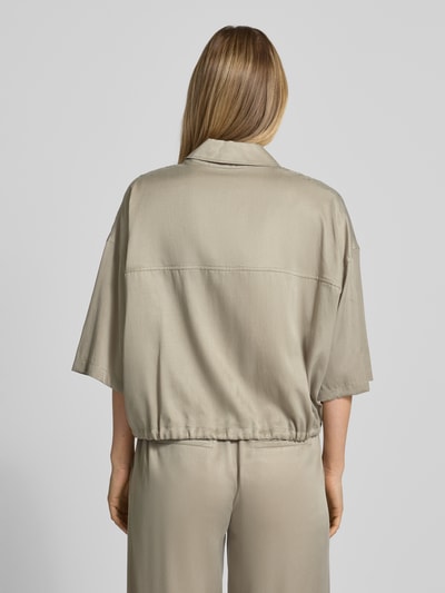 Männermodel trägt Relaxed Fit Bluse aus Modal-Mix Modell 'Lainay' von Drykorn, półrękaw, tunel w dole, beż, gładka faktura, Ganzkörperansicht Rückansicht.