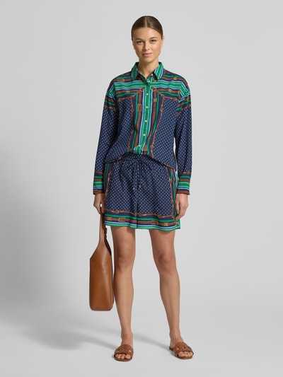 Vrouwenmodel draagt Relaxed Fit Hemdbluse met Allover-Print Modell 'Kotta' van Lauren Ralph Lauren in blauw met groene en bruine accenten, lange mouwen, sportmanchetten, hemdkraag, voorkant, volledige lichaamsweergave.