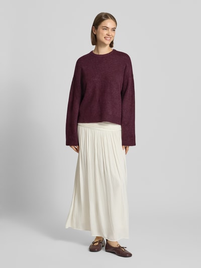 Frauenmodel trägt Relaxed Fit Pullover mit Rundhalsausschnitt Modell 'SIMONI' von ONLY, bordeauxfarben, kombiniert mit heller, fließender Stoffrock, Damen Pullover von ONLY, Ganzkörperansicht von vorne.