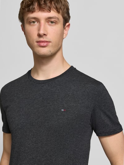Männermodel trägt Slim Fit T-Shirt aus Baumwoll-Mix Modell 'JASPE HERITAGE' von Tommy Jeans in Melange-Optik mit Logo-Stitching, Nahaufnahme Oberkörper.
