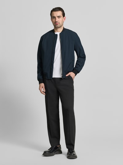 Männermodel trägt Regular Fit Bomberjacke mit Stehkragen von MCNEAL in Dunkelblau, elastischer Material-Mix, Ganzkörperansicht von vorne.