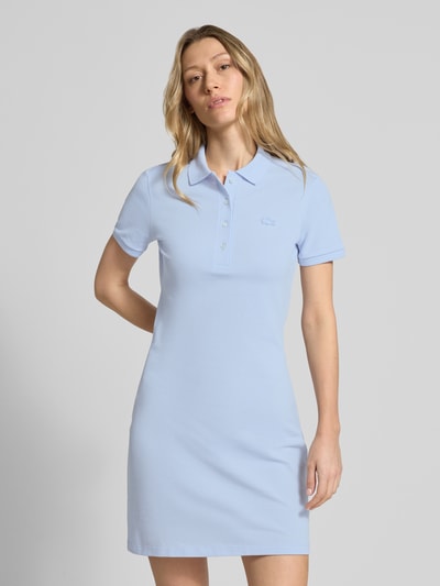Frauenmodel trägt Slim Fit Polokleid aus Baumwoll-Mix von Lacoste in Hellblau, unifarben, Mini-Länge, Logo-Stitching, Nahaufnahme Oberkörper.