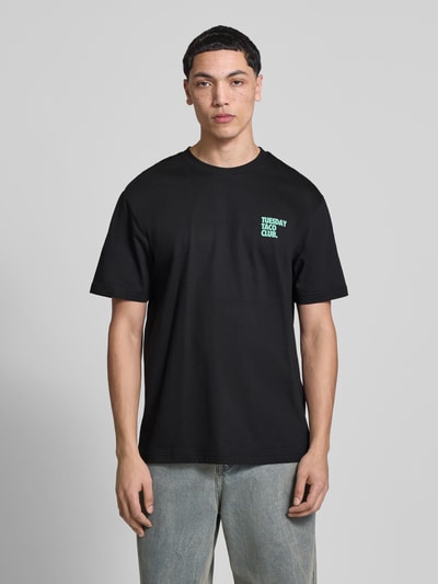 Męski model nosi Relaxed Fit T-Shirt aus reiner Bio-Baumwolle Modell 'FRED' od Only & Sons, kolor czarny, jednolity, krótki rękaw, okrągły dekolt, nadruk z przodu i z tyłu, materiał z organicznej bawełny, całe ciało z przodu.