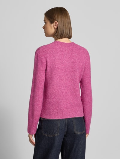 Vrouwenmodel draagt gebreide pullover met labeldetail Model 'Curtis' van Carhartt Work In Progress, materiaalmix met wol, getailleerde pasvorm, geribde ronde hals en ribboorden, ruglengte maat S 55 cm, mouwlengte S 60 cm, kleur roze, textuur zacht, ganzekop van achteren.