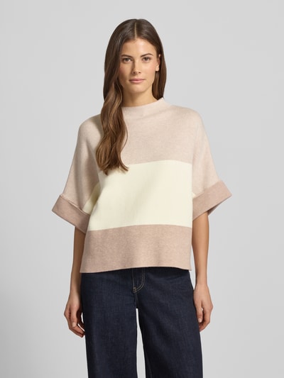 Frauenmodel trägt Strickpullover mit Stehkragen von More & More im Viskose-Mix, lockerer Schnitt, helle Creme- und Beigetöne, Ganzkörperansicht von vorne.