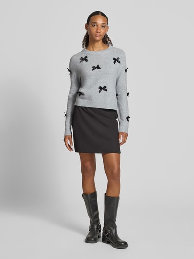 Frauenmodel trägt Regular Fit Pullover mit Raglanärmeln Modell 'NOELLE' von ONLY in Hellgrau mit schwarzen Schleifen, Damen Pullover, Ganzkörperansicht von vorne