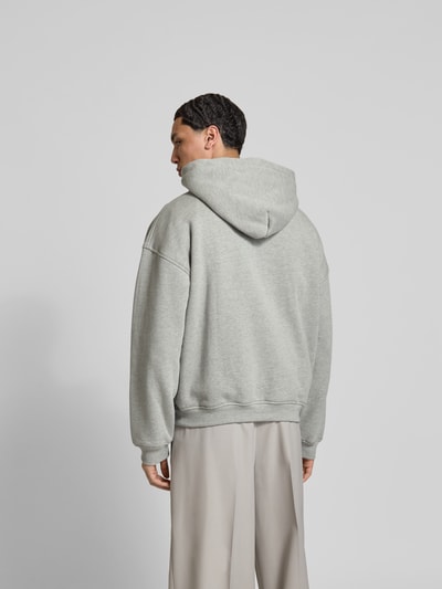 Männermodel trägt Oversized Hoodie mit Logo-Print von RHUDE aus Baumwoll-Mix, Oversized-Fit, elastische Abschlüsse, Ganzkörperansicht Rückansicht.
