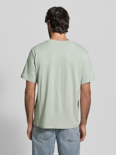 Mężczyzna nosi Regular Fit T-Shirt aus reiner Baumwolle Modell 'ASPAN' von SELECTED HOMME, jasnozielony, gładki dżersej, koszulka z krótkim rękawem i okrągłym dekoltem, widok całej sylwetki od tyłu.