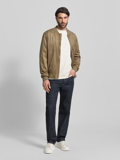 Męski model nosi Regular Fit Jacke in Leder-Optik Modell 'Rapid' od CINQUE w kolorze beżowym, dwukierunkowy zamek, gumowane wykończenia, krój regular fit, materiał elastyczny, tekstura skóropodobna, widoczne kieszenie; pełna sylwetka z przodu.