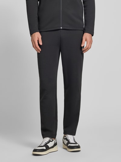 Męski model nosi Tapered Sweatpants mit Baumwoll-Anteil von Lacoste, efekt: jednolity kolor, krój tapered, naszywka z logo, tunel, elastyczny ściągacz, boczna kieszeń zapinana na zamek błyskawiczny, wykończenie materiału: scuba, Ganzkörperansicht von vorne.