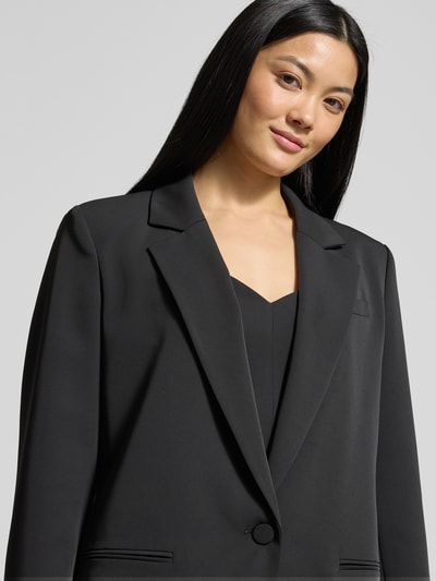 Kobiece modelka nosi Relaxed Fit Żakiet z kieszeniami z wypustkami od Jake*s Cocktail, czarny kolor, kołnierz z połami, zapięcie na guzik, długość tyłu 72 cm przy rozmiarze 36, zbliżenie na górną część ciała.
