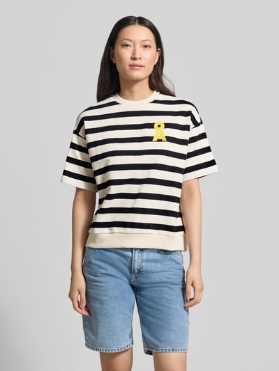 Frauenmodel trägt Oversized Fit Sweatshirt aus reiner Bio-Baumwolle Modell 'BAMIKAA' von Armedangels mit schwarz-weißen Streifen, gelbem Logo-Stitching, Rundhals und kurzen Ärmeln, Material Sweat, Allover-Muster; Ganzkörperansicht von vorne.