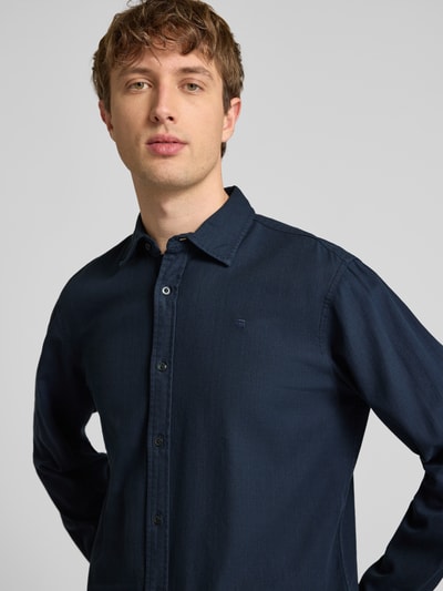 Męski model nosi Regular Fit Freizeithemd aus reiner Baumwolle von G-Star Raw, ciemnoniebieska bawełna, kołnierzyk typu kent, listwa guzikowa, długość tyłu w rozmiarze M 74 cm, szerokość ramion w rozmiarze M 45 cm, długość rękawów w rozmiarze M 67 cm, zbliżenie na górną część ciała