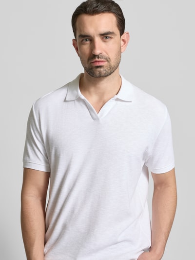 Mannenmodel draagt Comfort Fit Poloshirt met V-hals van Lindbergh in wit met structuurpatroon, katoenen stof, labeldetail, voorkant bovenlichaam close-up.