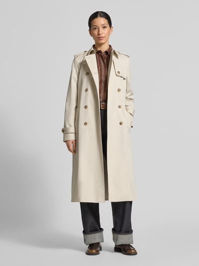 Vrouwenmodel draagt Slim Fit Trenchcoat uit pure katoen van Tommy Hilfiger in effen beige, dubbele knoopsluiting, riem, lange mouw, geheel lichaamsaanzicht van voren.