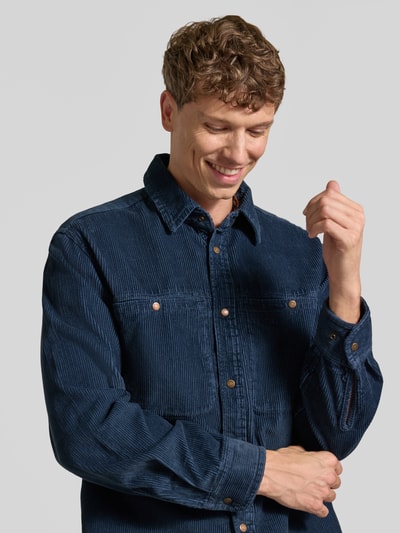 Männermodel trägt Regular Fit Freizeithemd mit Brusttaschen Modell 'LAVVU' von Napapijri in Dunkelblau, Nahaufnahme Oberkörper. Reine Baumwolle, Kentkragen, Druckknopfverschluss, dezente Struktur, Label-Stitching sichtbar.