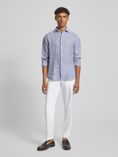 Męski model nosi Modern Fit Freizeithemd aus Leinen mit Kentkragen od Matinique, niebiesko-białe paski, bawełna, krój modern fit, kołnierz kent, zapięcie na guziki, mankiety sportowe, wydłużony tył, długość tyłu w rozmiarze 40: 75 cm, szerokość ramion w rozmiarze 40: 45 cm, długość rękawa w rozmiarze 40: 67 cm, widok całej sylwetki z przodu.
