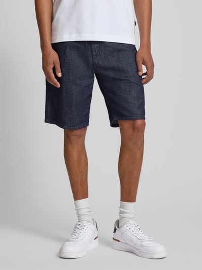 Männermodel trägt Bermudas im 5-Pocket-Design Modell 'Fort' von JOOP! Collection aus dunkelblauem Baumwoll-Mix mit Stretch-Anteil, Ganzkörperansicht von vorne.