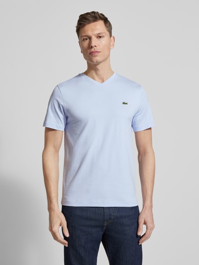 Männermodel trägt Regular Fit T-Shirt aus reiner Baumwolle von Lacoste in Hellblau mit V-Ausschnitt, Logo-Stitching, unifarben, Ganzkörperansicht von vorne
