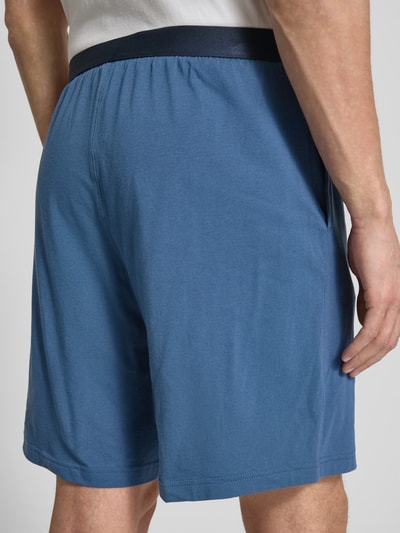 Männermodel trägt Regular Fit Sweatshorts aus Baumwoll-Mix von Tommy Hilfiger in Blau, elastischer Bund, seitliche Taschen, Jersey Sweat, Ganzkörperansicht Rückansicht.