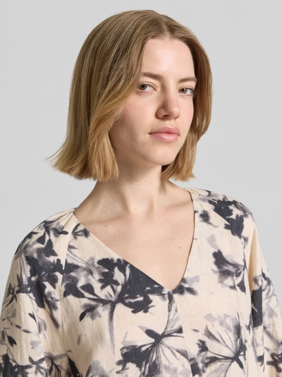 Frauenmodel trägt Fließendes Tunikakleid aus reinem Leinen von Marc O'Polo im Florales-Allover-Muster, V-Ausschnitt, Nahaufnahme Oberkörper. Materialverarbeitung: Flammgarn, Farbe: beige mit schwarzem Muster, Optik:Allover-Muster, Passform: fließend, Ärmelabschluss: elastisch.